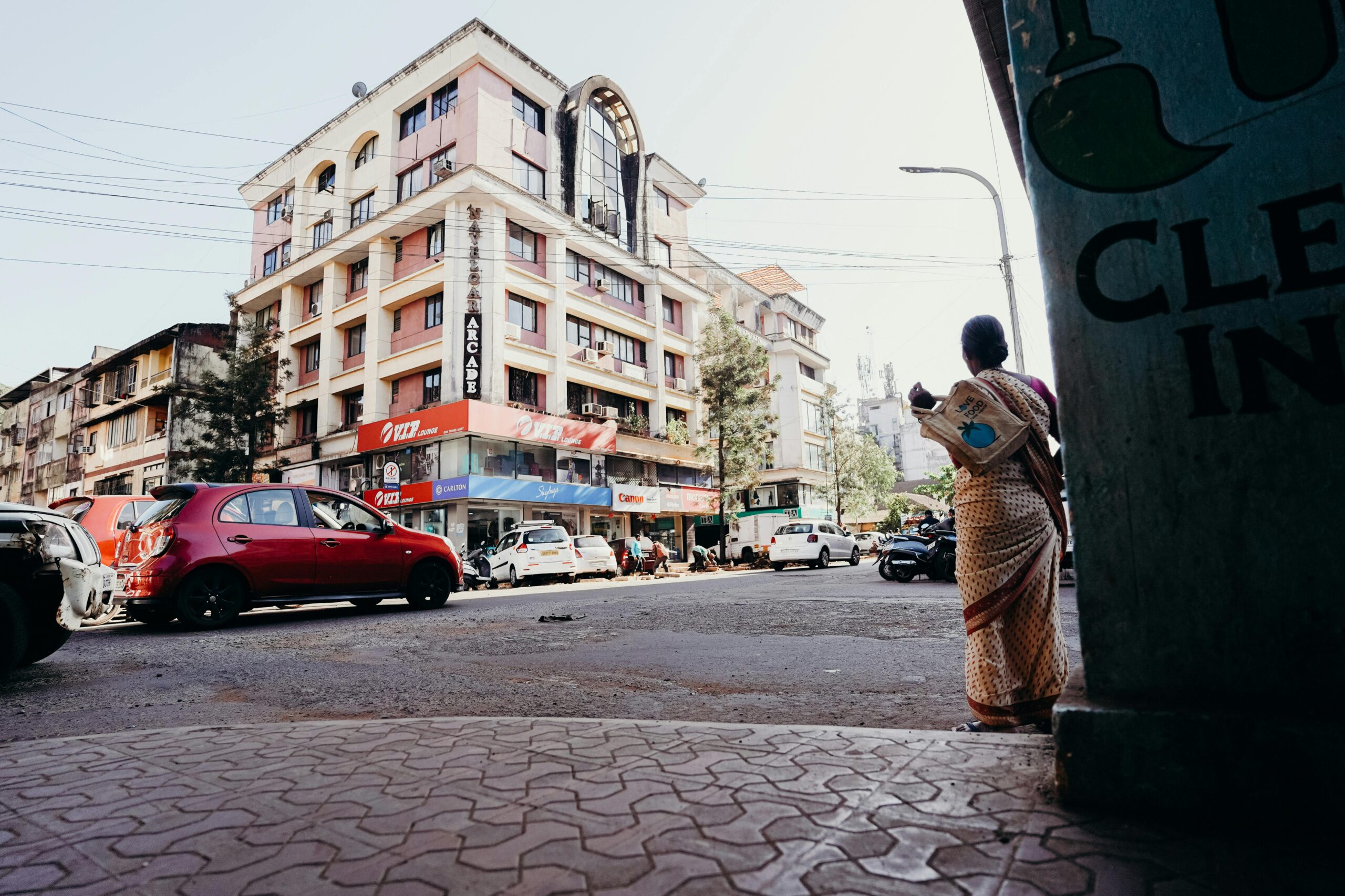 Man in Brown Jacket Standing on Sidewalk Near Cars and Buildings